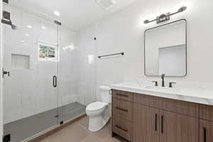 Full bathroom featuring vanity, a marble finish shower, and light tile patterned floors