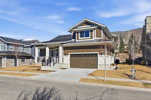 Craftsman inspired home featuring a standing seam roof, a porch, a garage, and driveway