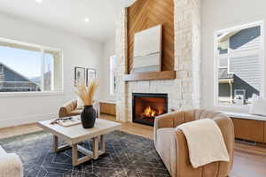 Living room with dark wood finished floors, a stone fireplace, and recessed lighting