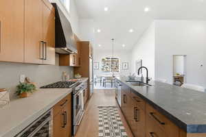 Kitchen with gas range, wood finish cabinets, plenty of natural light, hanging light fixtures, and a high ceiling