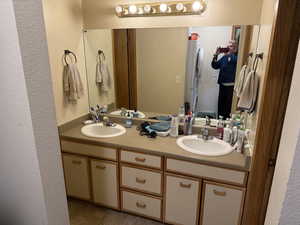 Bathroom featuring a textured wall and double vanity