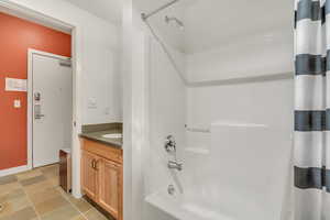Bathroom featuring shower / bath combo with shower curtain, vanity, and light tile patterned floors