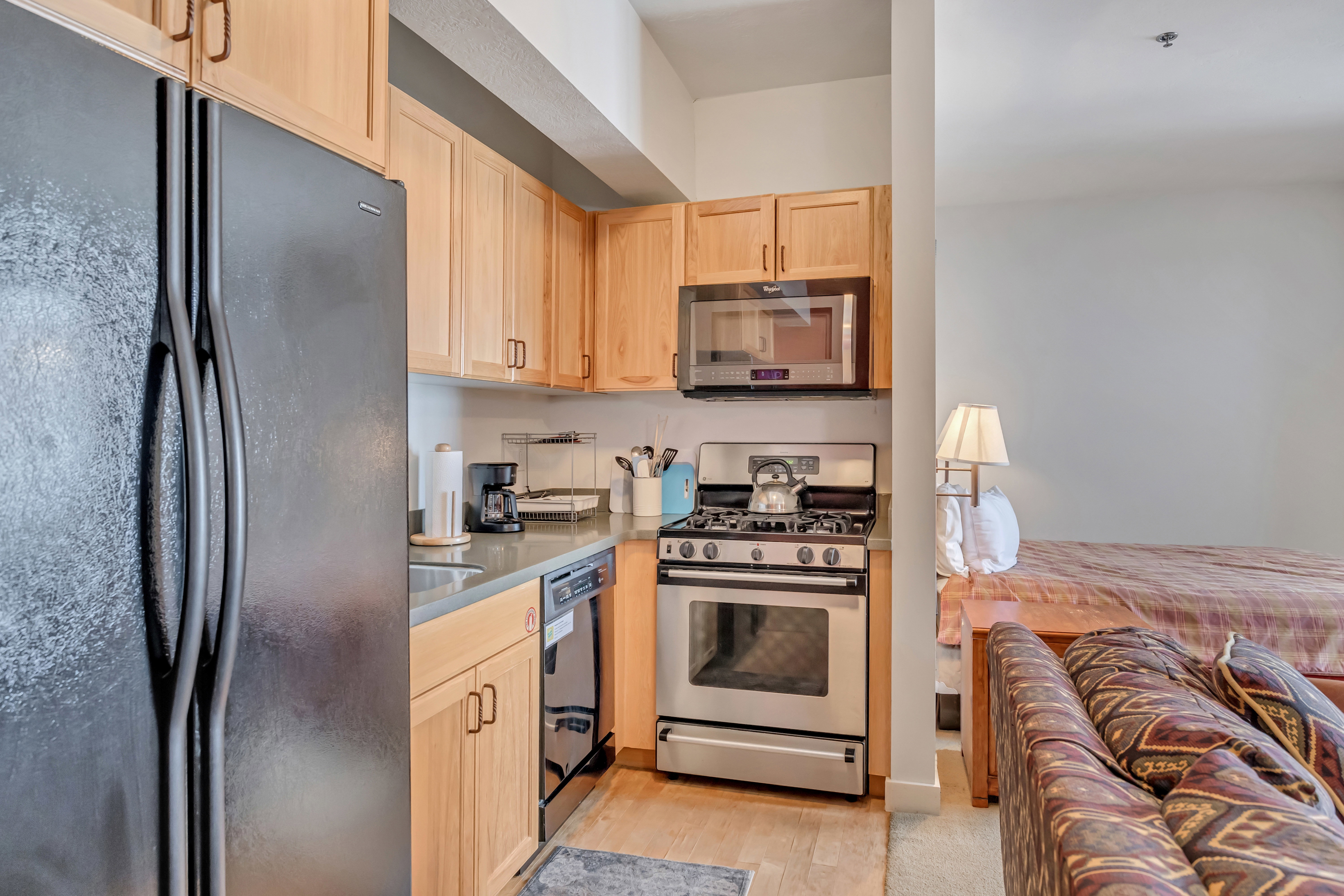 Kitchen with black appliances, light wood finish cabinetry, and light wood-style flooring