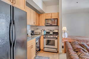Kitchen with black appliances, light wood finish cabinetry, and light wood-style flooring
