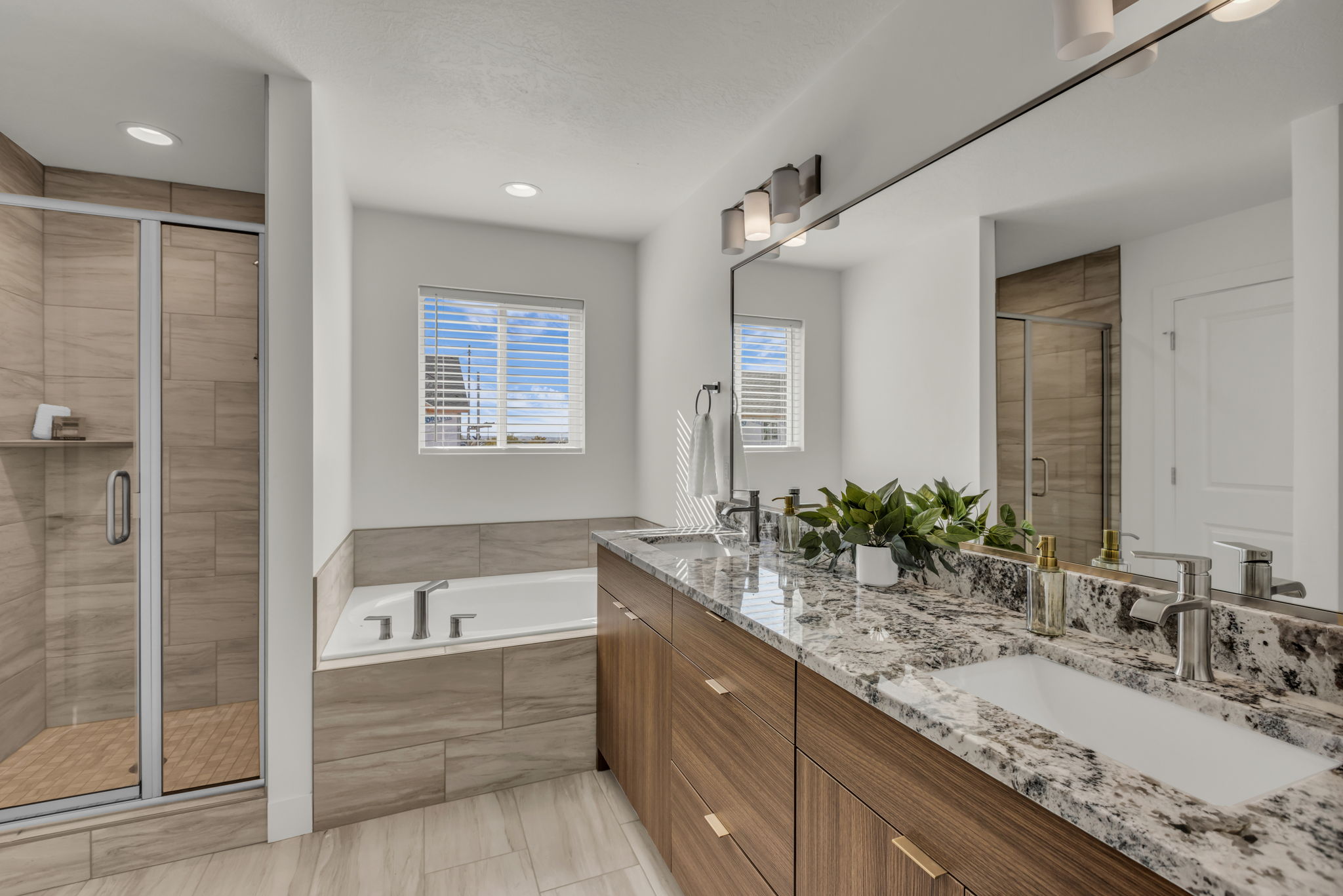 Full bath with a shower stall, double vanity, and a garden tub