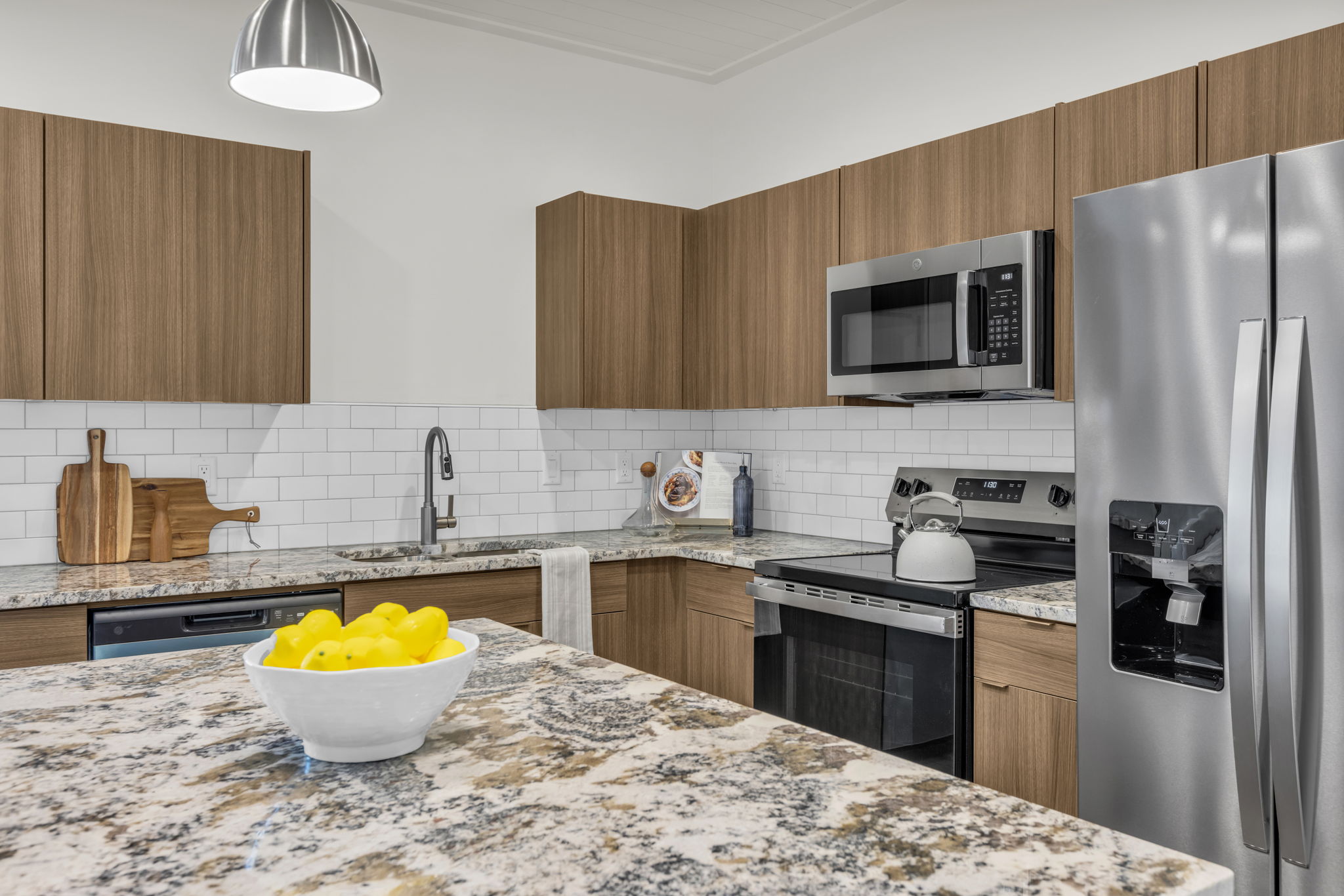 Kitchen with wood finish cabinets, stainless steel appliances, light stone countertops, modern cabinets, and tasteful backsplash