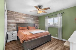 Bedroom featuring an accent wall, LVP floors, and ceiling fan