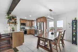 Dining room with healthy amount of natural light, light tile patterned floors, and suspended lighting