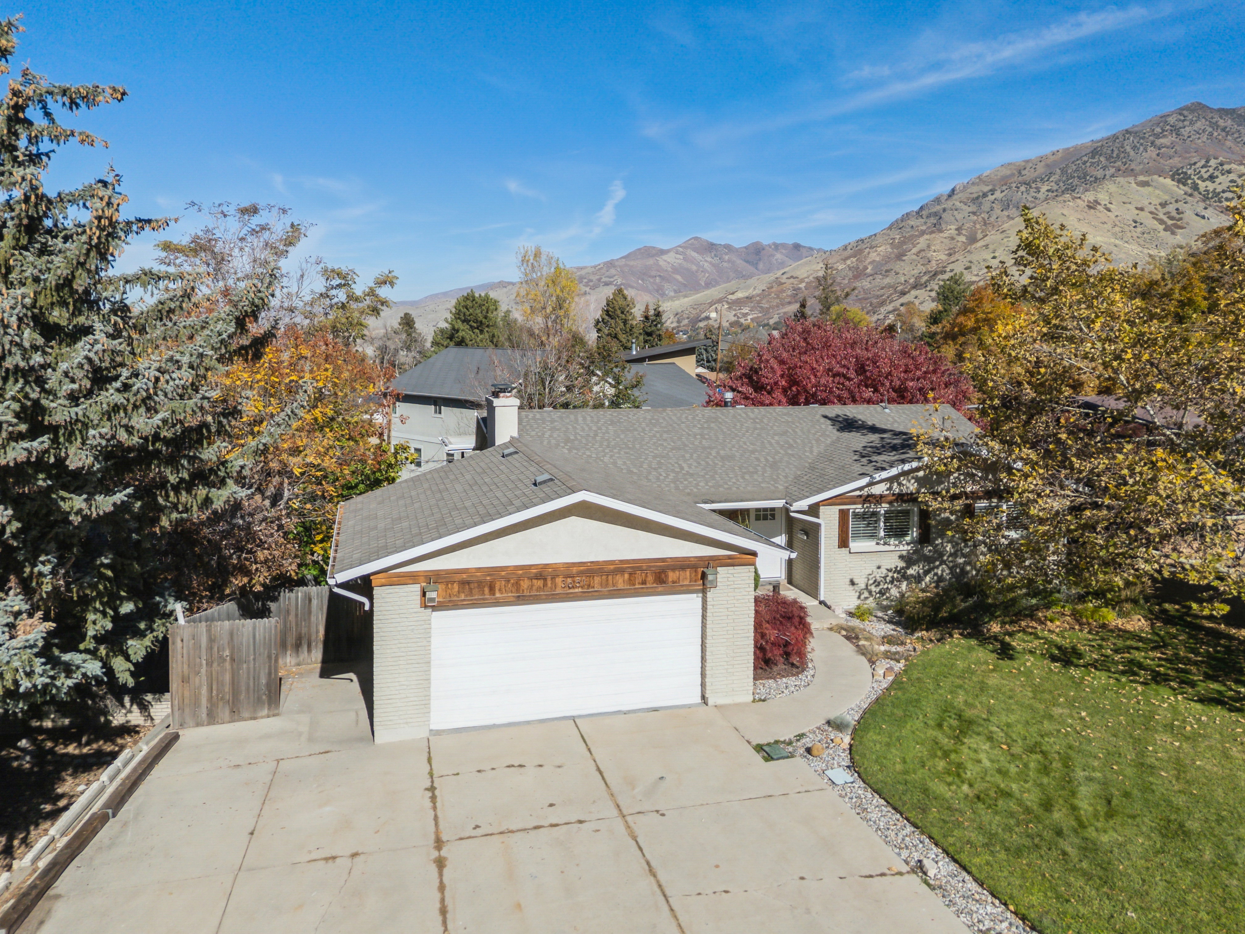 Single story home with brick siding, a garage, concrete driveway, and a mountain view