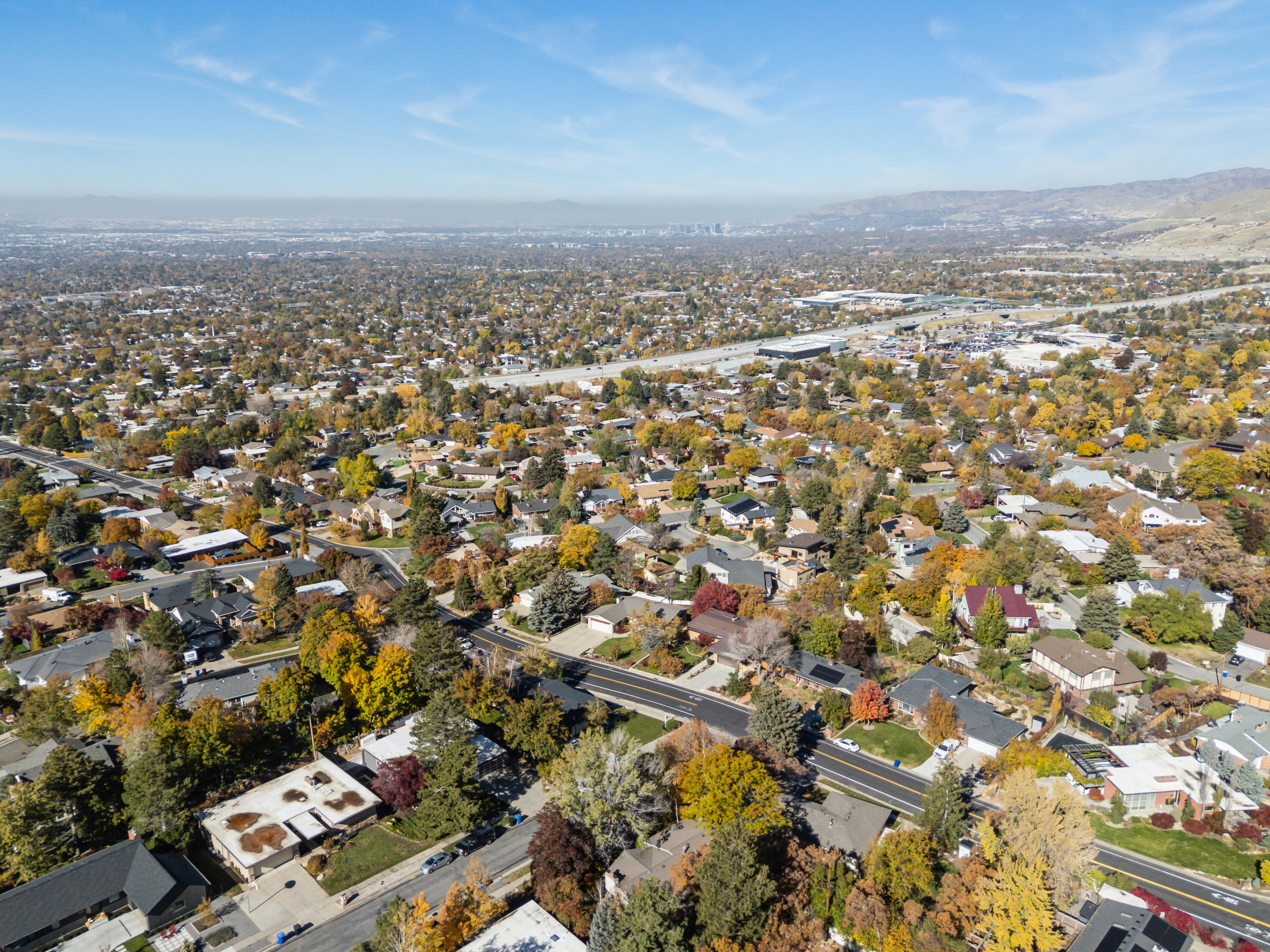 Aerial view of property and surrounding area featuring nearby suburban area and a mountainous background