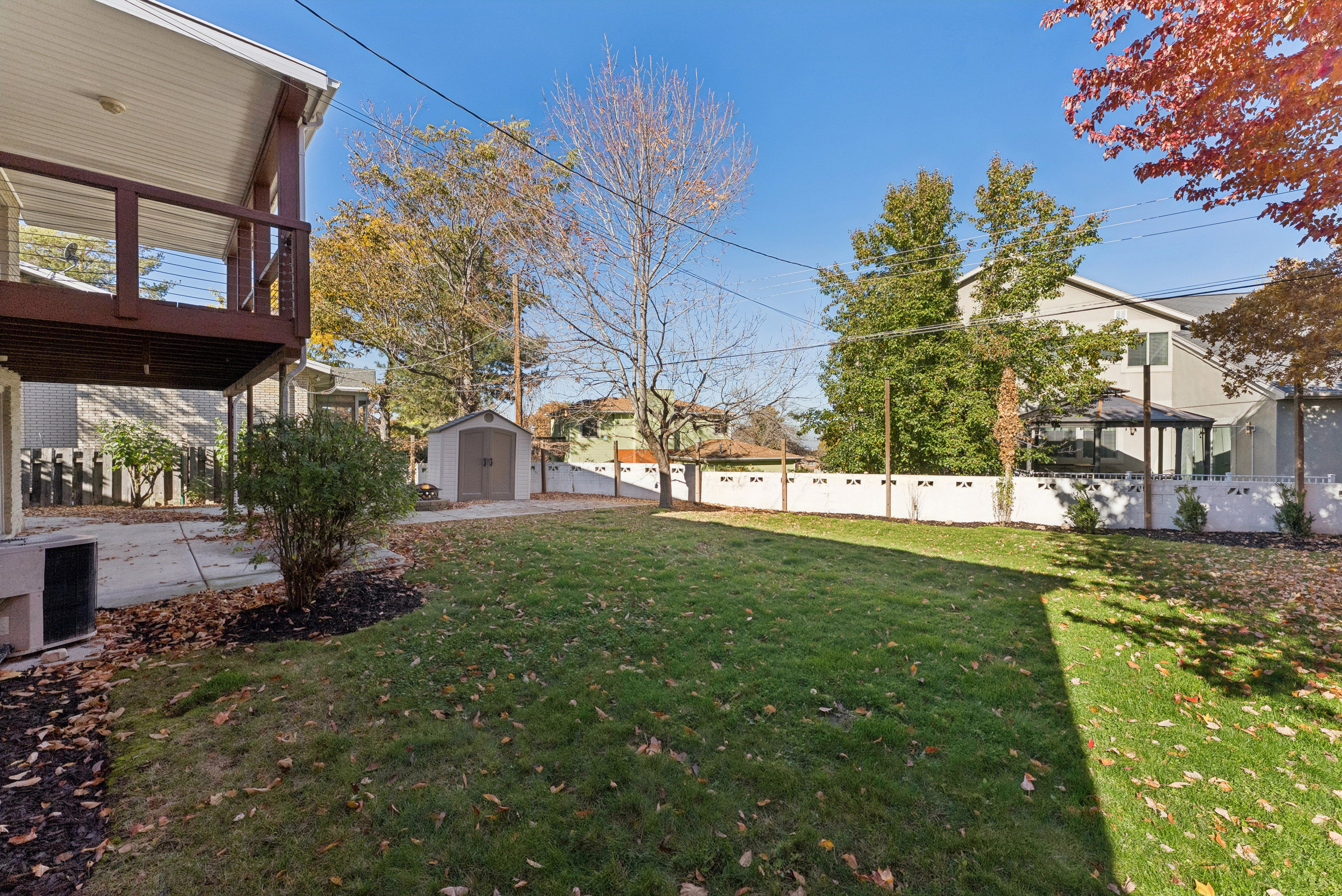 Fenced backyard featuring a storage unit and a residential view