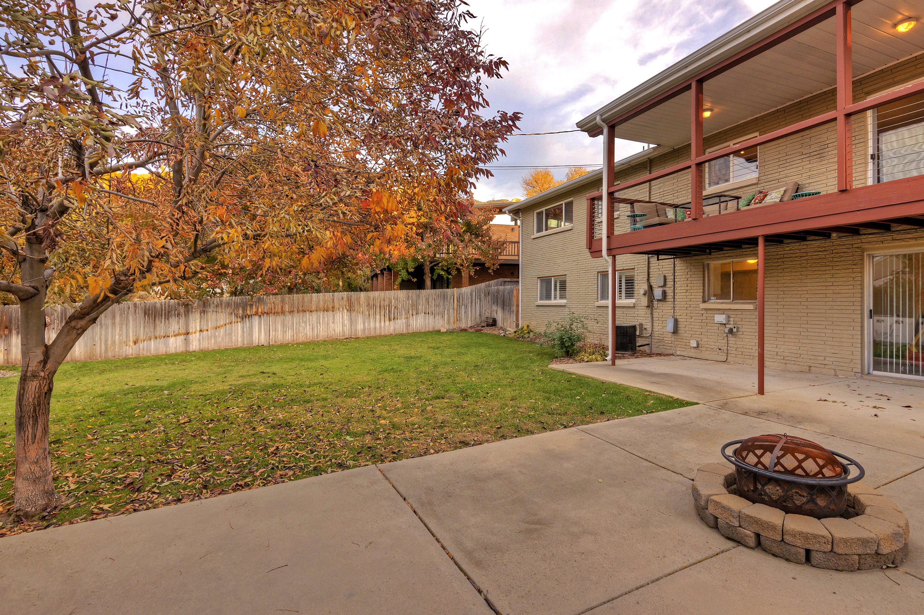 Fenced backyard featuring a patio area, an outdoor fire pit, and a balcony