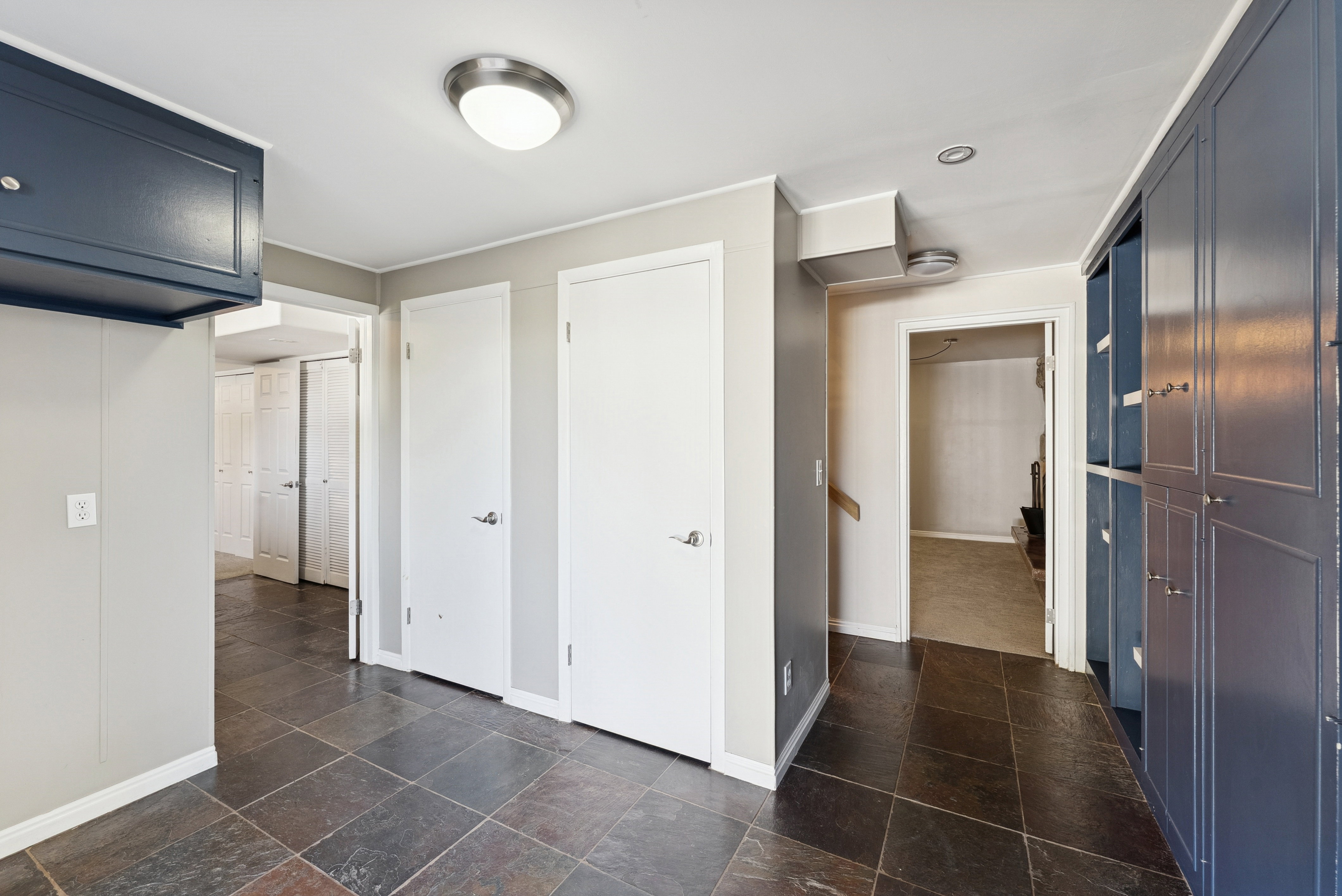 Corridor featuring stone tile floors and baseboards