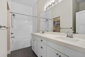 Full bathroom featuring double vanity,  shower combination, and dark tile patterned floors