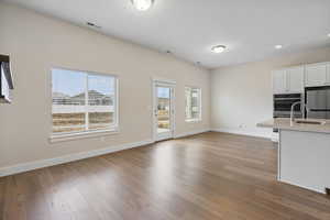 Kitchen with white cabinets, light wood-type flooring, stainless steel appliances, open floor plan, and recessed lighting