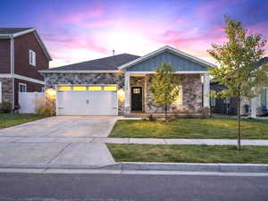 View of front of house with stone siding, concrete driveway, board and batten siding, and an attached garage