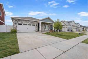 Single story home featuring a front yard, concrete driveway, board and batten siding, and stone siding