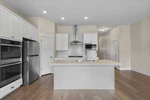 Kitchen with stainless steel appliances, light countertops, white cabinetry, dark wood-style flooring, and recessed lighting