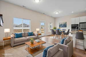 Living area with light wood finished floors and recessed lighting