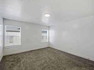 Carpeted spare room with baseboards and a textured ceiling