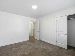 Unfurnished bedroom featuring dark carpet and a closet