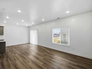 Unfurnished living room featuring dark wood-style flooring and recessed lighting