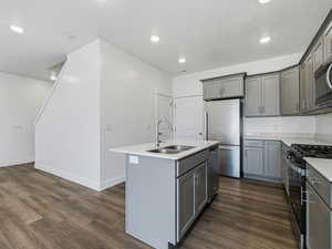 Kitchen featuring gray cabinetry, a kitchen island with sink, stainless steel appliances, dark wood-style floors, and recessed lighting