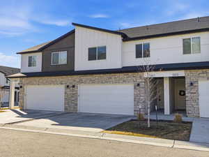 View of front facade featuring stone siding, driveway, and a garage