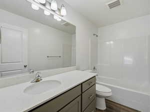 Bathroom with vanity, shower / washtub combination, and dark wood finished floors