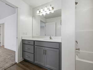Full bathroom with vanity, bathtub / shower combination, and dark wood-style floors