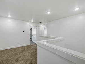 Hall featuring dark colored carpet and an upstairs landing