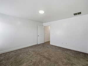 Empty room with dark colored carpet and baseboards