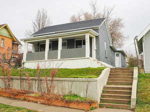 Bungalow-style home with a shingled roof, covered porch, and brick siding