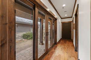 Doorway with wood-type flooring, ornamental molding, and recessed lighting