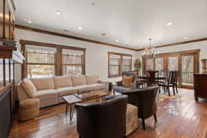 Living room featuring wood-type flooring, ornamental molding, plenty of natural light, and a chandelier