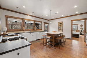 Kitchen featuring white cabinets, pendant lighting, light wood-type flooring, dark countertops, and white dishwasher