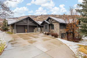 Craftsman inspired home with stone siding, driveway, a chimney, and a garage