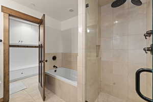 Full bath with a garden tub, a stall shower, and light tile patterned flooring