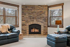 Carpeted living room featuring a large wood-burning fireplace.