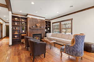 Living area featuring crown molding, light wood-style flooring, a glass covered fireplace, and recessed lighting