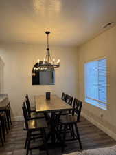 Dining room featuring dark wood-style flooring, a textured ceiling, and a chandelier