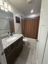 Full bath featuring vanity, shower / tub combo with curtain, and light tile patterned floors