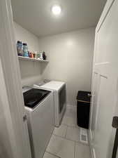 Laundry area with washer and dryer and light tile patterned flooring