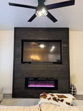 Detailed view of a large fireplace, ceiling fan, and a textured ceiling