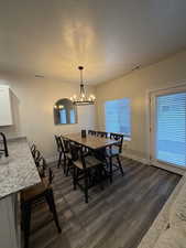 Dining space with a textured ceiling, dark wood finished floors, and hanging lights