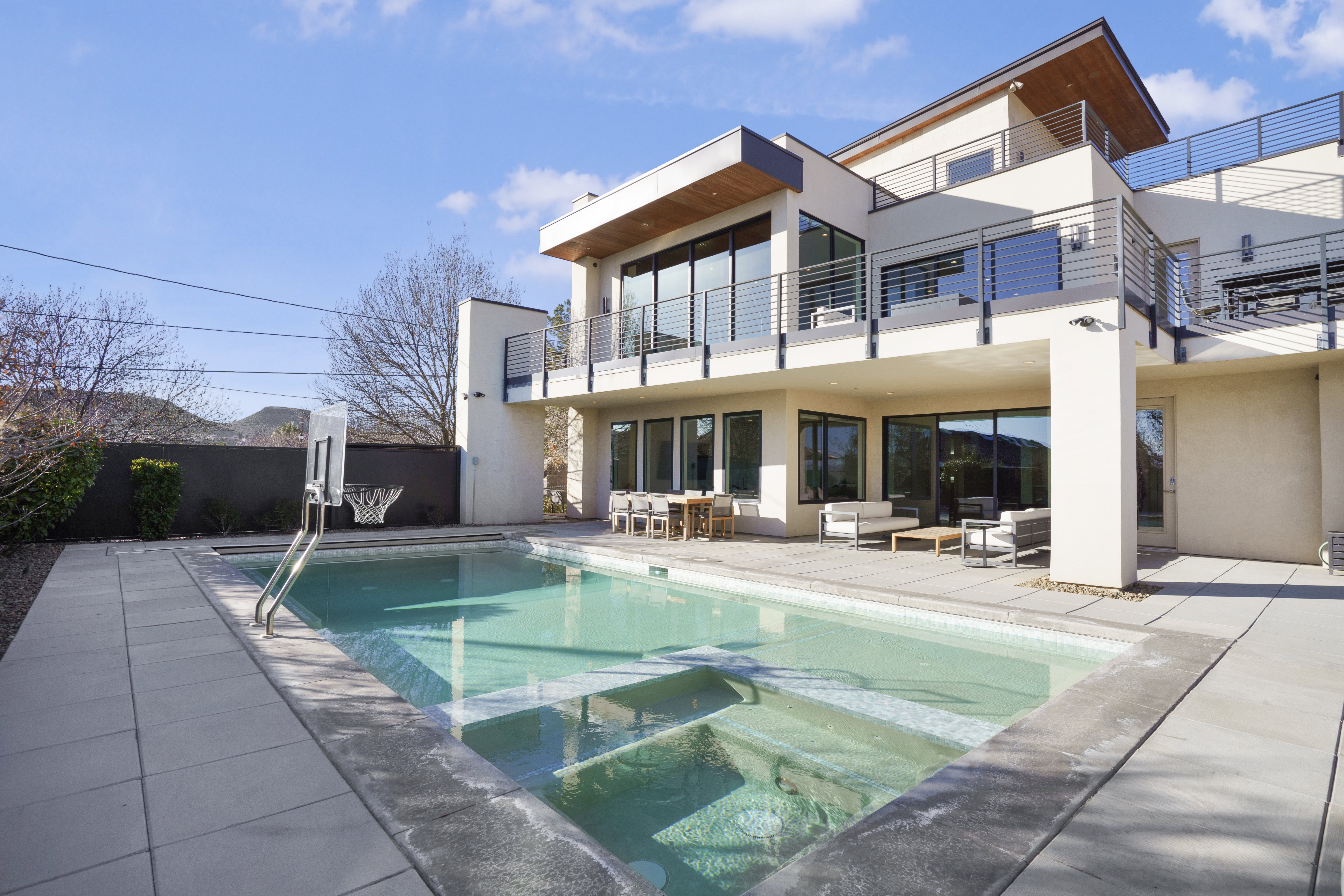 Back of property with a pool with connected hot tub, stucco siding, an outdoor living space, and a patio