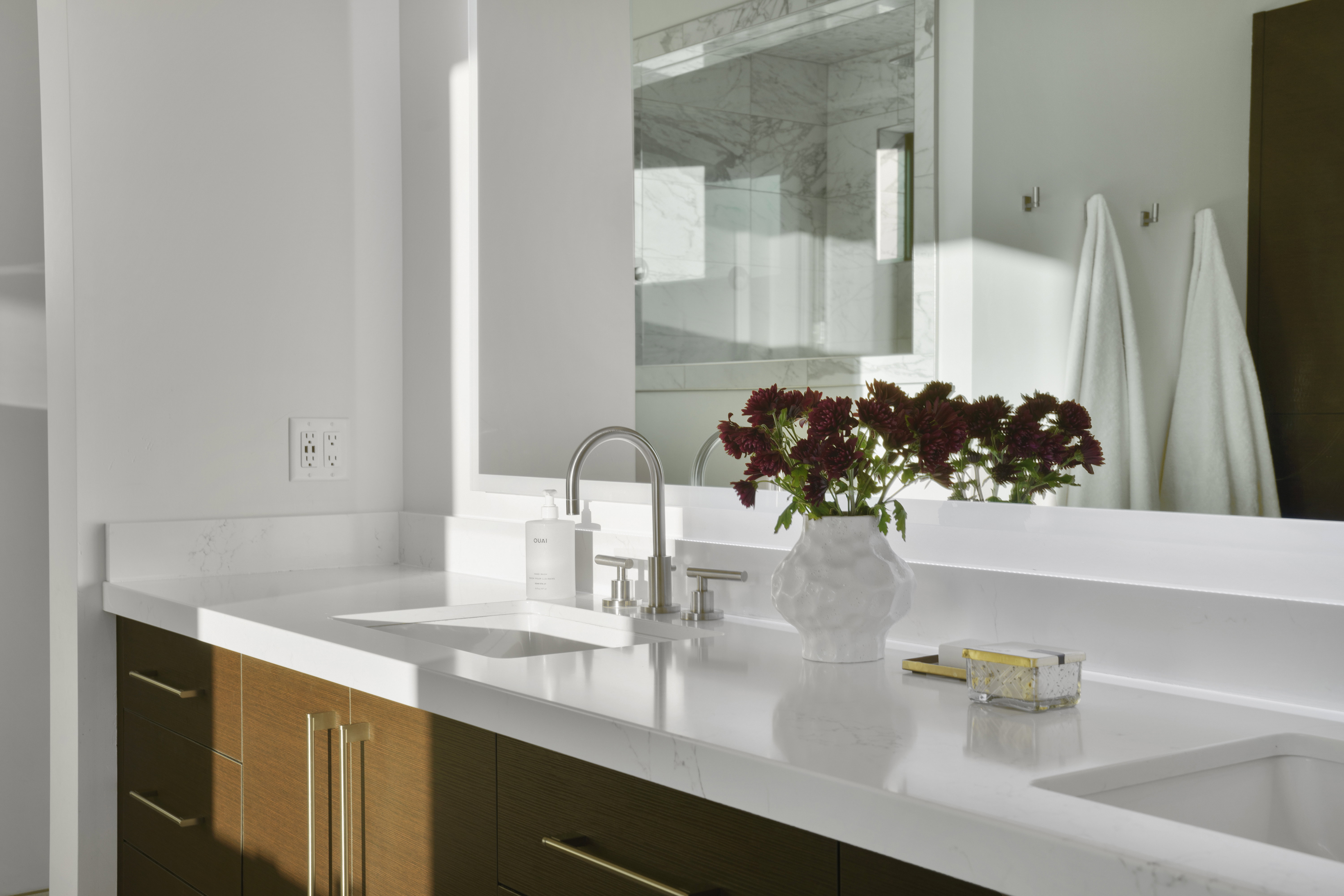 Full bath with double vanity and a marble finish shower