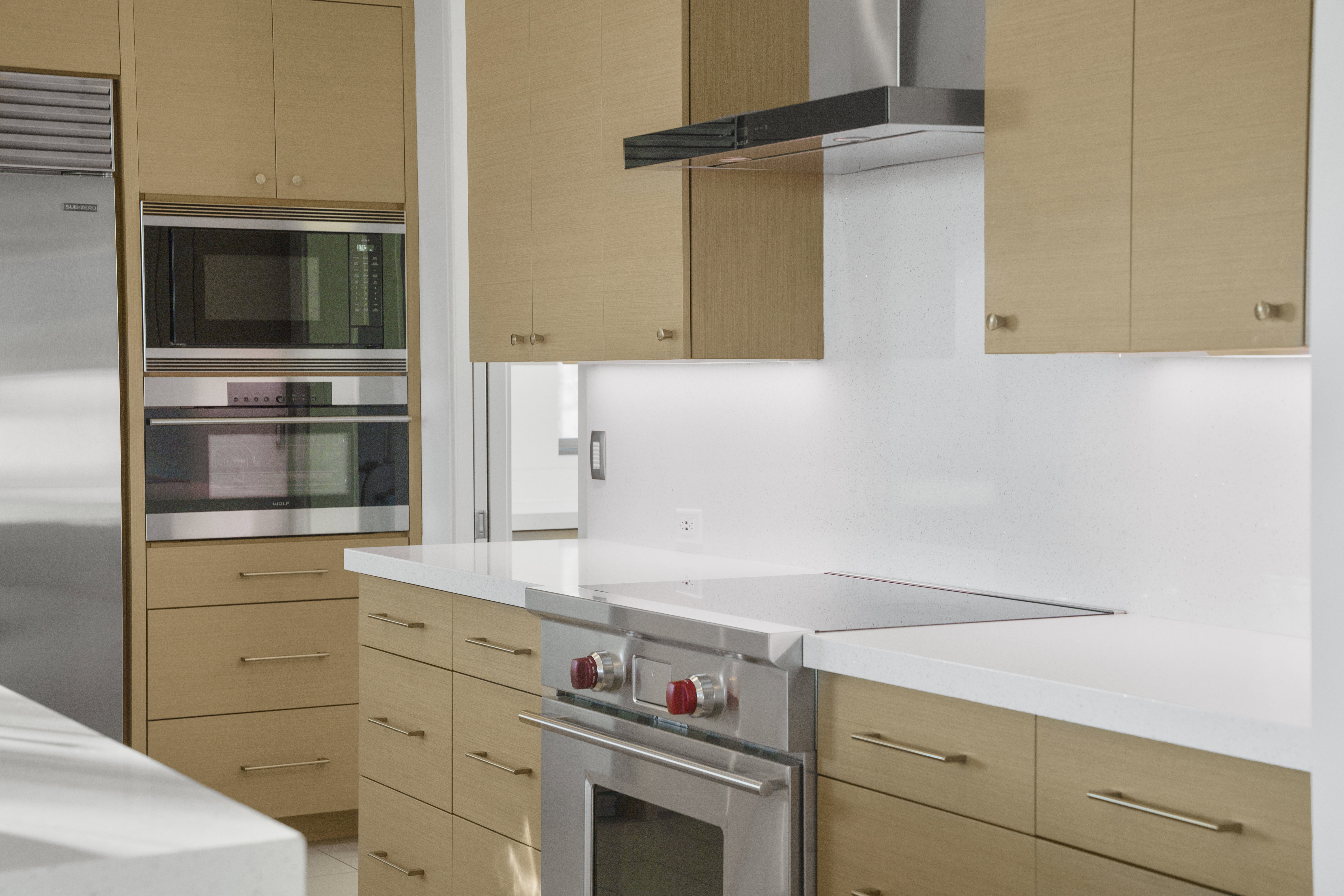 Kitchen with light wood finish cabinets, built in appliances, and modern cabinets