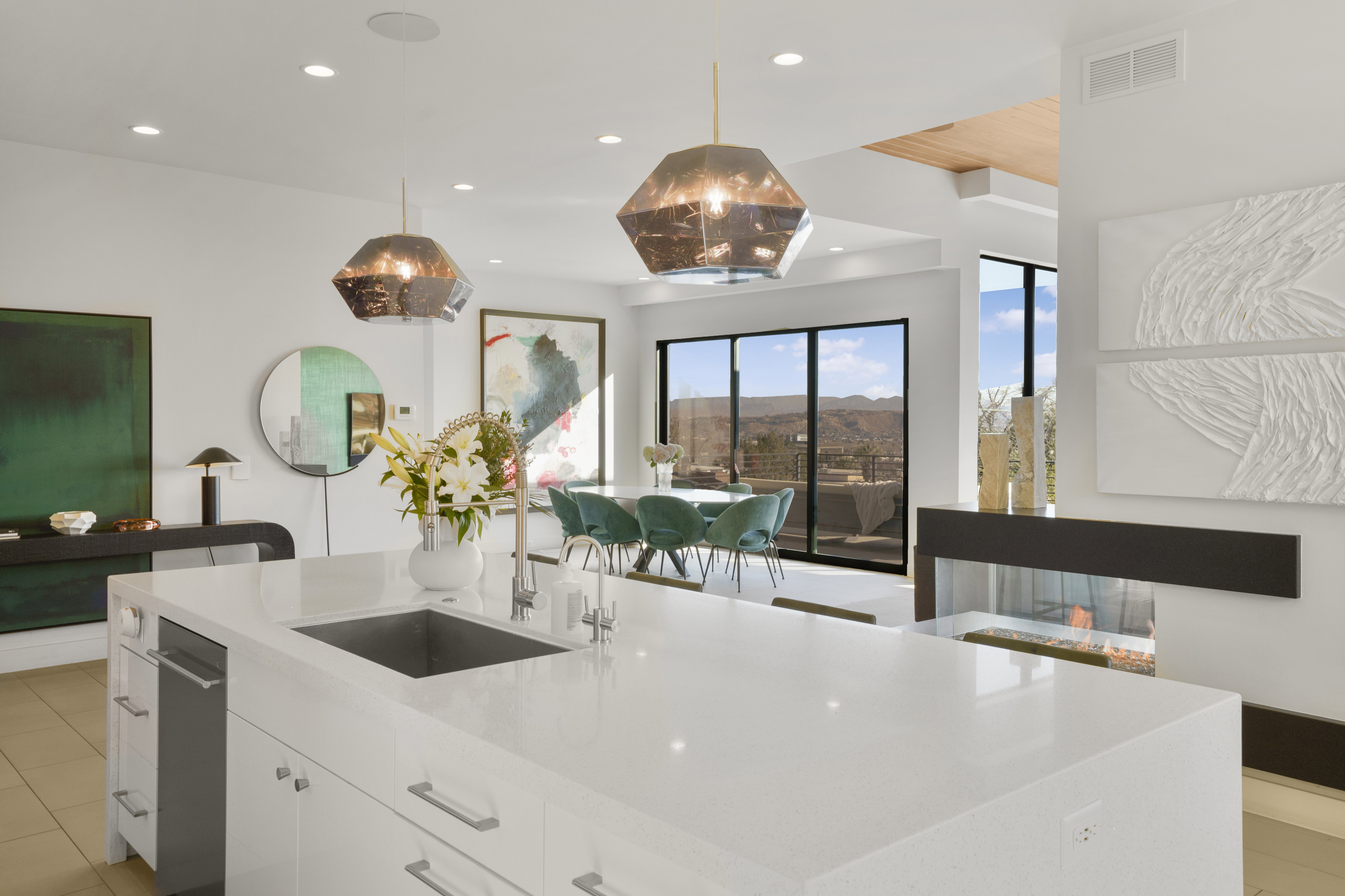 Kitchen with white cabinets, light stone countertops, and hanging light fixtures