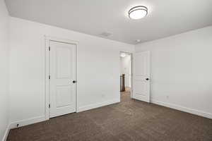 Unfurnished bedroom featuring baseboards and dark colored carpet